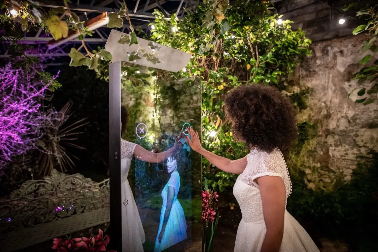 Mirror X example: a guest taps the photo booth screen during a garden celebration